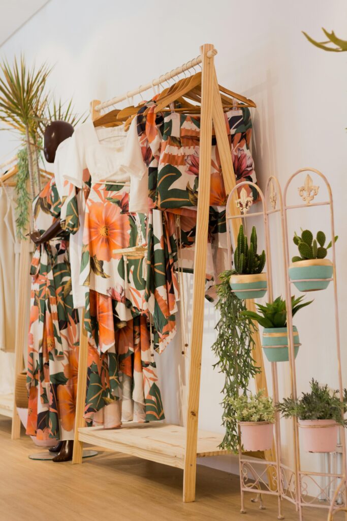 Floral print clothing elegantly displayed in a modern boutique with lush green plants for decoration.